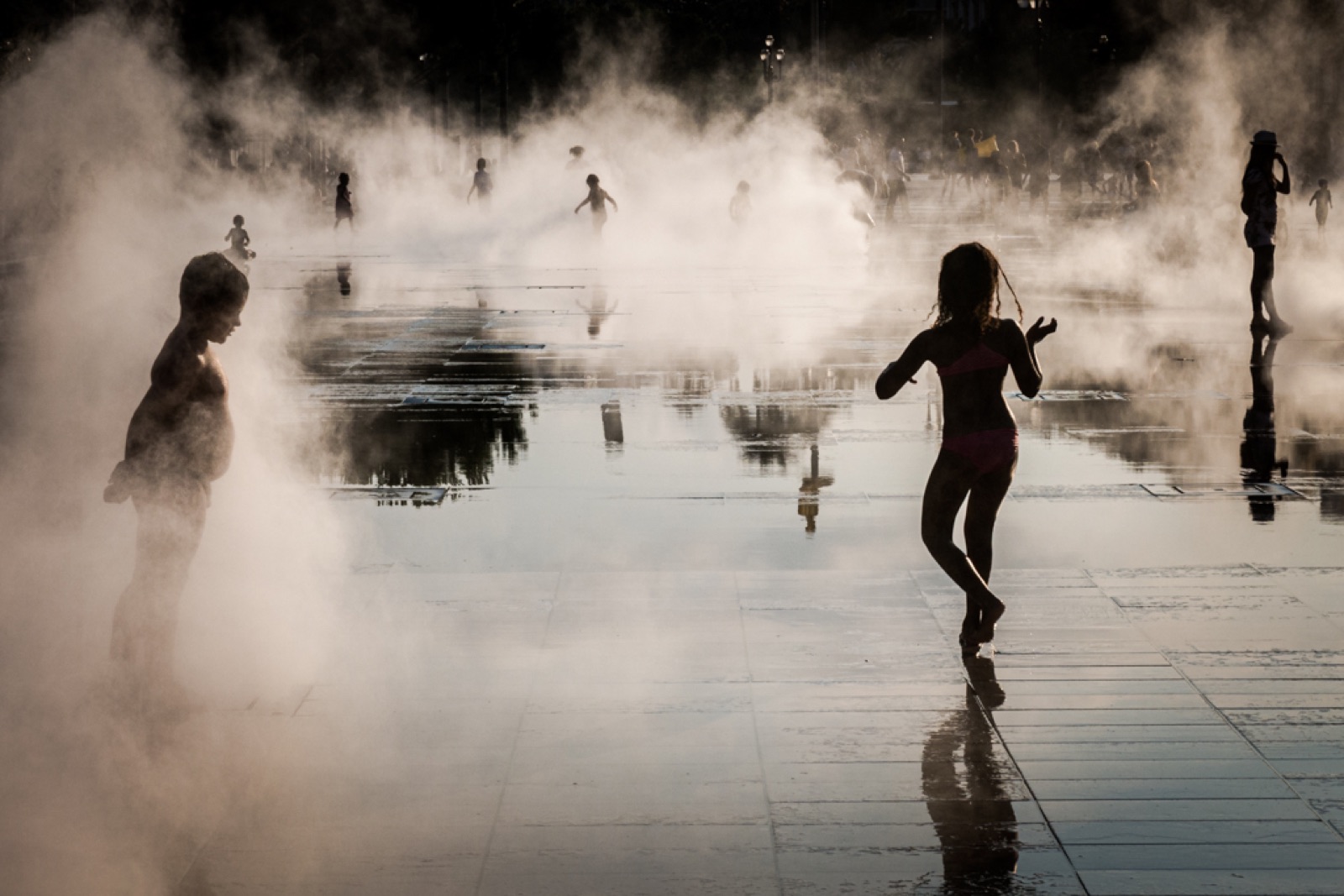 Children playing in mist and reflections on a water mirror